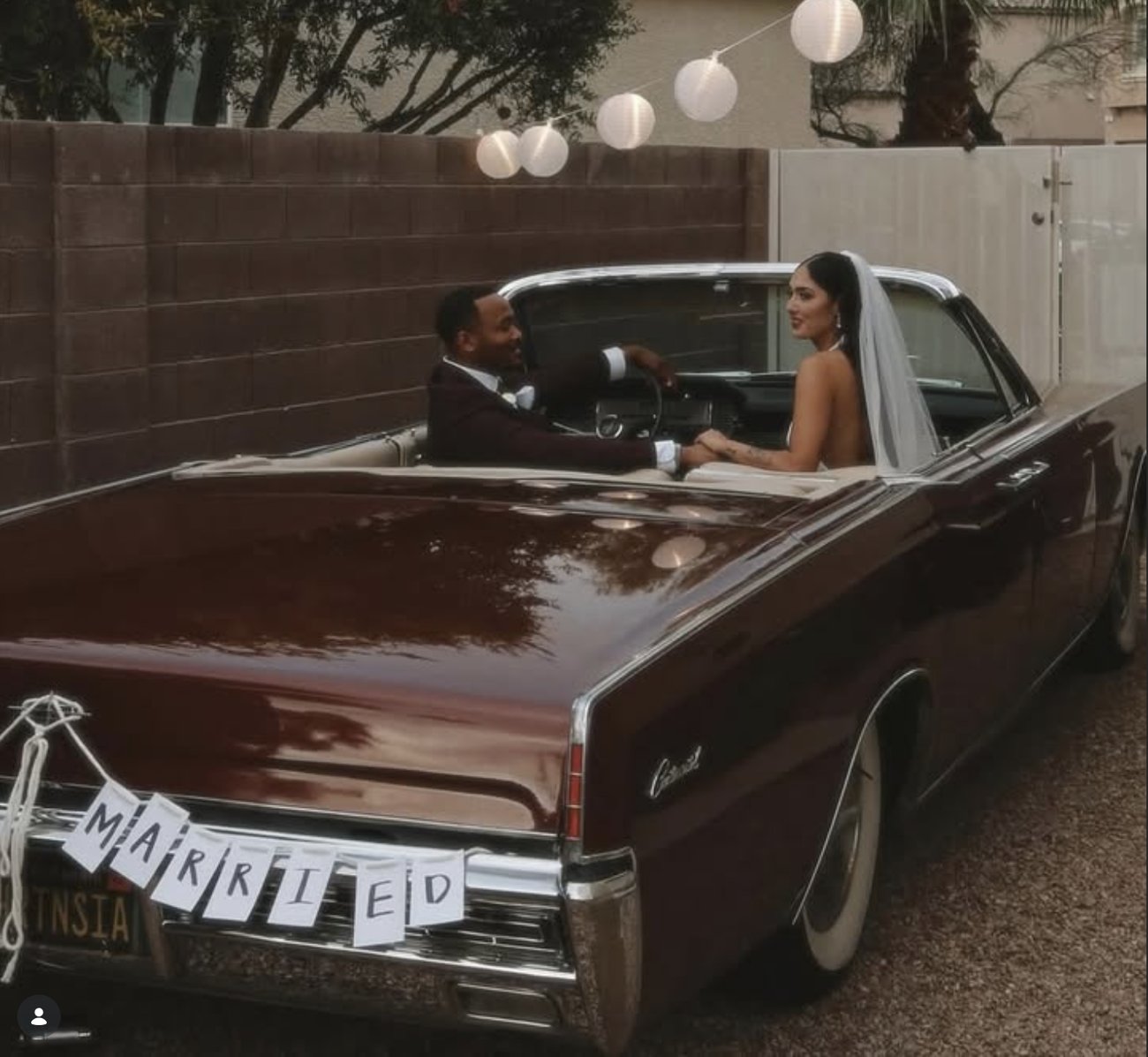 Bride and groom in a vintage convertible after their wedding