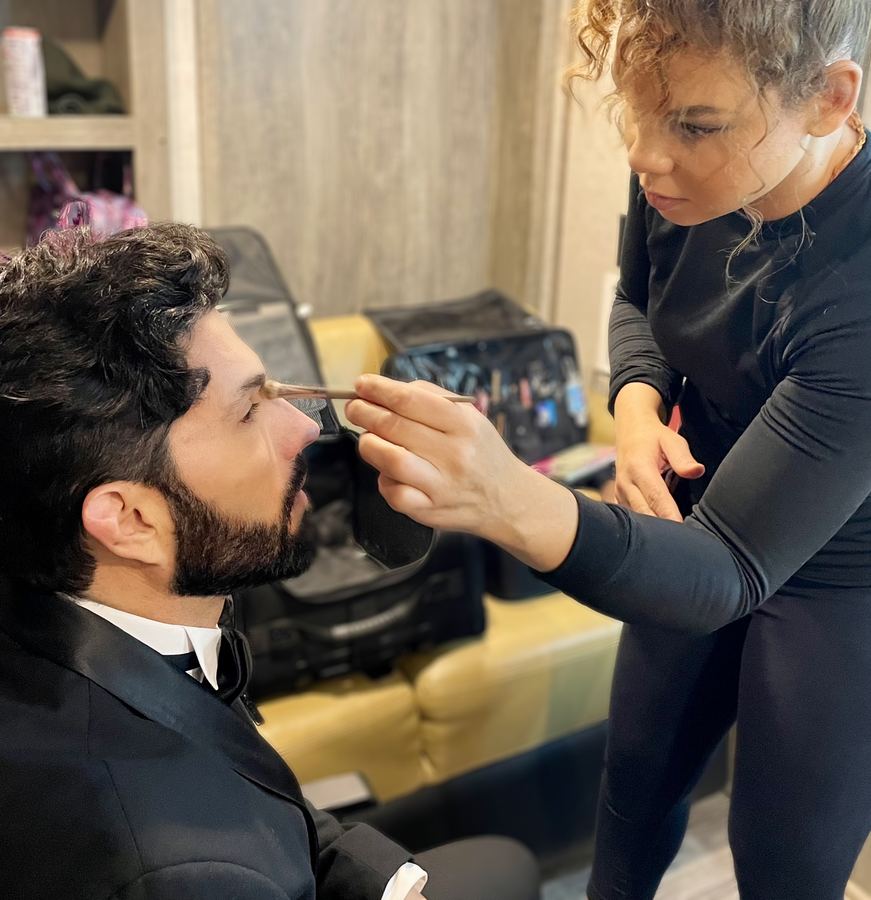 Applying makeup to a client in a tuxedo